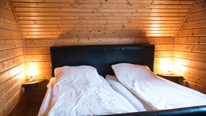 A wooden cabin room with a bed, two bedside lamps, and a window. - House 47 the House to Stay for Holidays (Oberharz am Brocken)