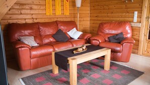 A cozy room with a brown leather sofa, a wooden coffee table, and a patterned rug. - House 47 the House to Stay for Holidays (Oberharz am Brocken)