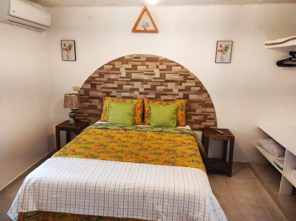 A bedroom with a bed, a nightstand, a lamp, and a wall-mounted air conditioner. - Bay View Apt Quiet Area Weekly - Monthly Discount (Samaná)