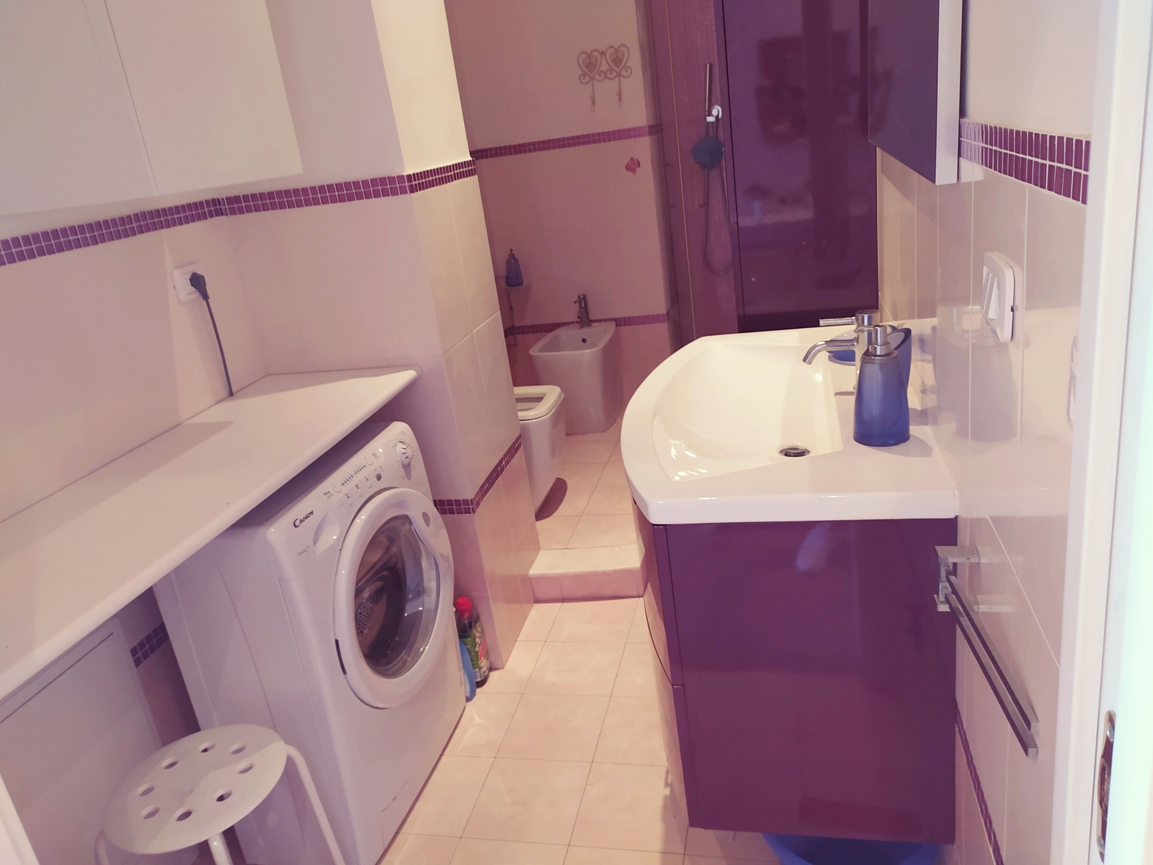 Une petite salle de bain équipée d’un lave-linge, de toilettes et d’un lavabo.