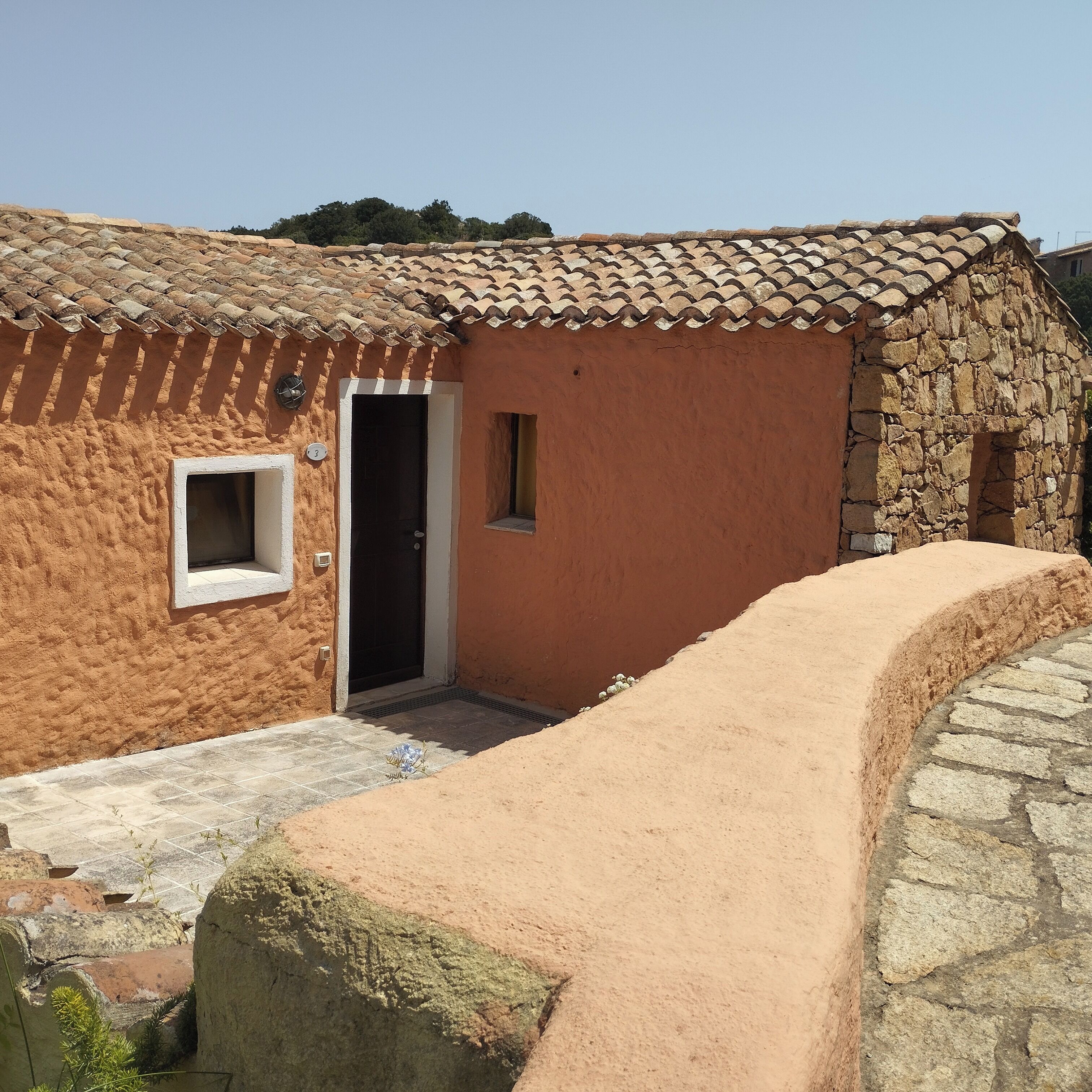 Un edificio rustico con tetto in tegole, una piccola finestra e una porta.