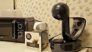 Une machine à café, un four à micro-ondes et une boîte de capsules de café espresso Nespresso Dolce Gusto.