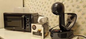 A coffee maker, a microwave, and a box of Nespresso Dolce Gusto espresso.