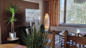 Une pièce avec une plante en pot, une lampe, une chaise et une table.