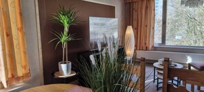 A room with a potted plant, a lamp, a chair, and a table.