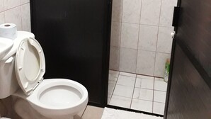 Un baño con inodoro, alfombra blanca y puerta negra.