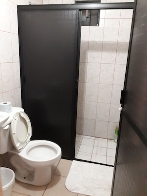 Un baño con inodoro, alfombra blanca y puerta negra.