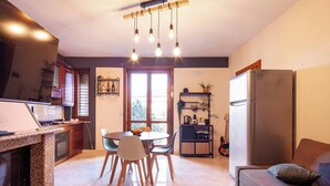 Una cocina moderna con encimeras de granito, un comedor con sillas, un refrigerador y un sofá.