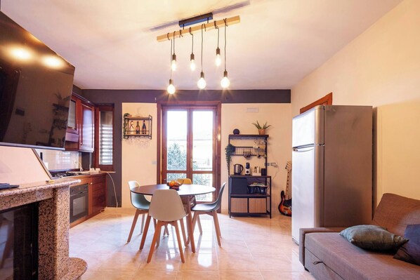 Une cuisine moderne avec des plans de travail en granit, un coin repas avec des chaises, un réfrigérateur et un canapé.
