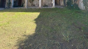 Un edificio histórico con un patio, arcos de piedra y una zona ajardinada.