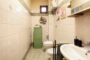 Une salle de bain avec deux toilettes, un lavabo, un miroir et une fenêtre.