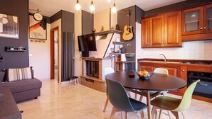 Una cocina moderna con armarios de madera, un comedor con mesa y sillas redondas, un televisor y una guitarra.