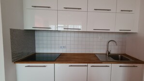 A kitchen with white cabinets, a wooden countertop, a sink, and a backsplash. - Features of Good And Night (Neuss)