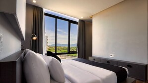 Ett modernt hotellrum med en stor säng, ett skrivbord och utsikt över bergen.