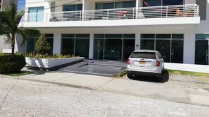 A modern building with a two-story entrance, a car parked in front, and a sign reading 'PLATINO'. - Aparta-suit Exclusive Rodadero (Santa Marta)