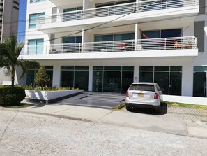 A modern building with a two-story entrance, a car parked in front, and a sign reading 'PLATINO'. - Aparta-suit Exclusive Rodadero (Santa Marta)