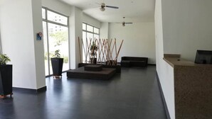 A spacious lobby with a reception desk, seating area, and large windows allowing natural light. - Aparta-suit Exclusive Rodadero (Santa Marta)