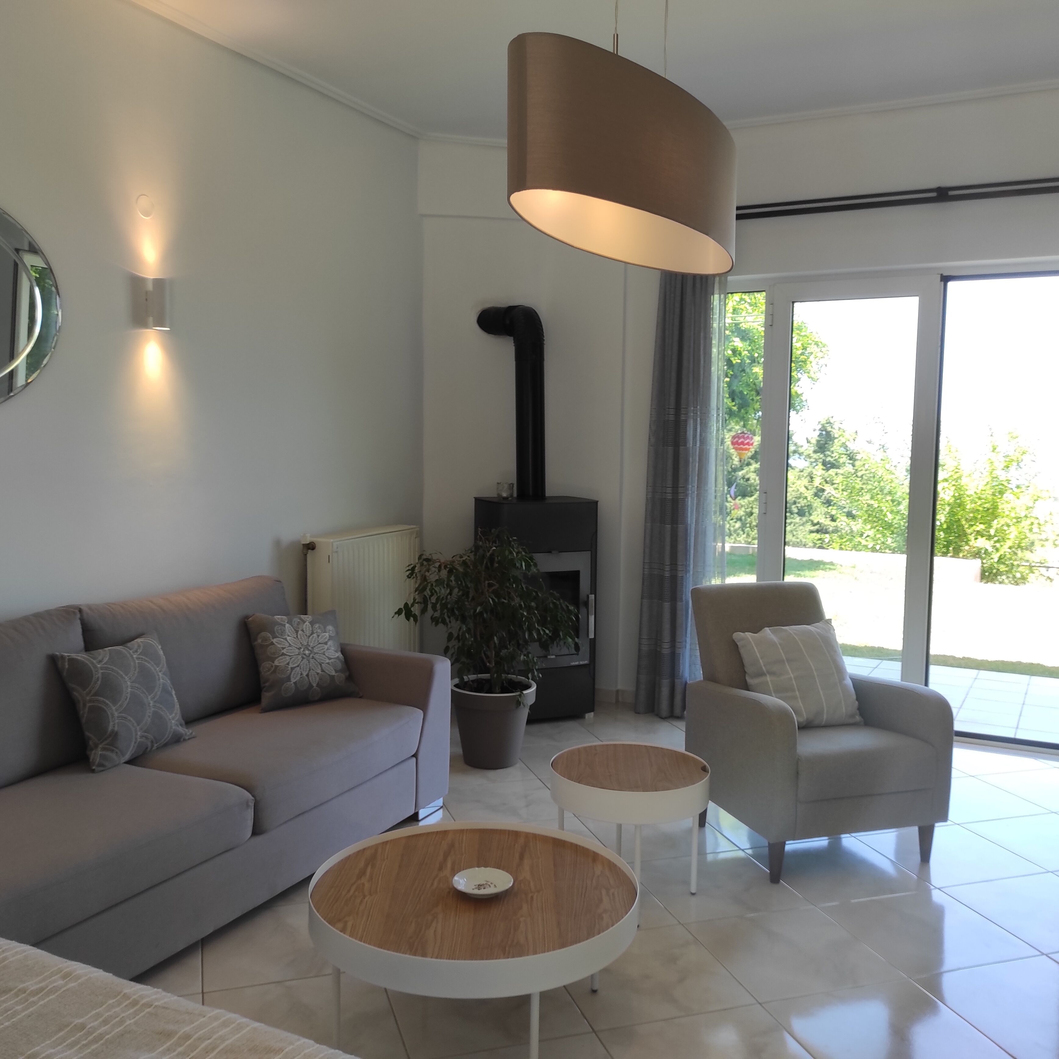 Een moderne woonkamer met een bank, twee fauteuils, een salontafel, een open haard en een groot raam.