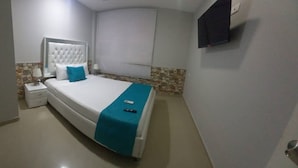 A neatly arranged bedroom with a bed, bedside table, and a TV mounted on the wall.
