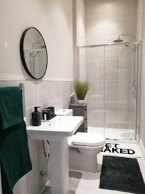 Un baño moderno con lavamanos, inodoro y cabina de ducha de vidrio.
