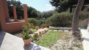A courtyard with potted plants, a tiled patio, and a tree. - Room-pelagos Studios by Frangki (Aegina)