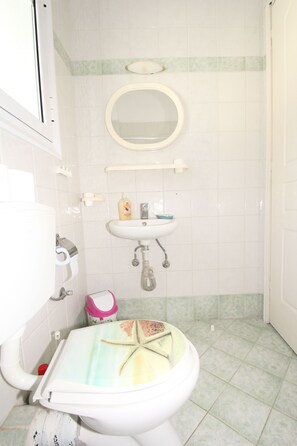 A bathroom with a toilet, sink, and mirror. - Room-pelagos Studios by Frangki (Aegina)