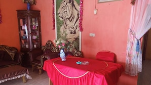 A room with a red table, a sofa, a cabinet, and a painting on the wall.