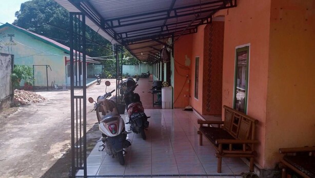 A covered outdoor area with a tiled floor, benches, and parked motorcycles.