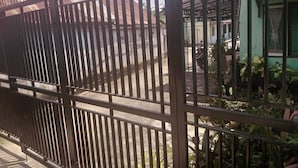 A gated area with a metal fence, a green building with windows, and a parked motorcycle.