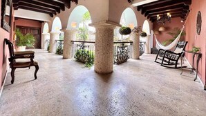 A spacious courtyard with stone columns, arches, and a hammock. - 8aps-4 Luxury House in the Historic Center With Pool Air Conditioning and Wifi (Cartagena)