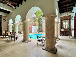 A pool area with stone columns, outdoor seating, and a view of a garden. - 8aps-4 Luxury House in the Historic Center With Pool Air Conditioning and Wifi (Cartagena)