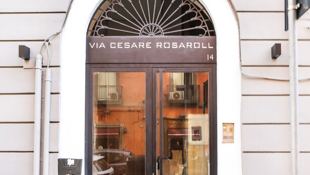 A building entrance with a sign reading "VIA CESARE ROSAROLL 14".