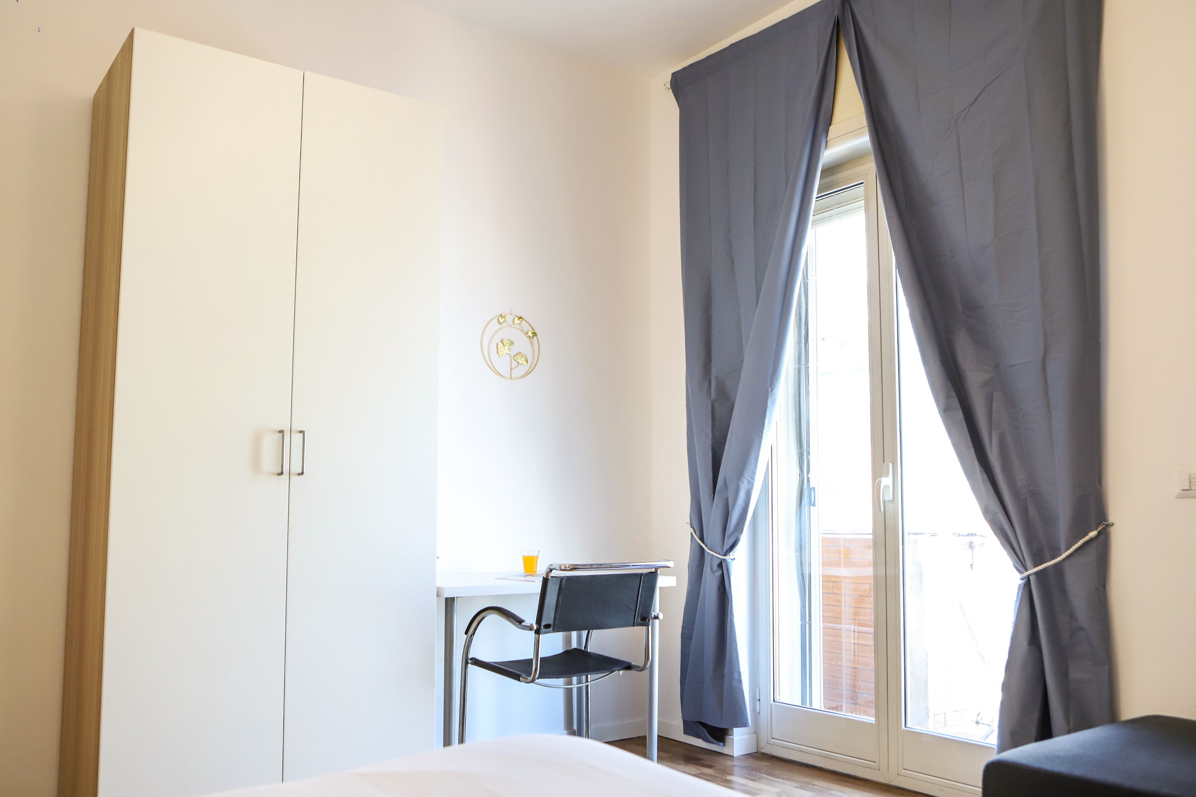 A bedroom with a bed, a desk, a chair, and a wardrobe.