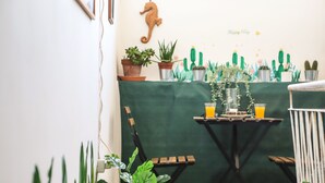 A dining area with a green table, chairs, and potted plants.