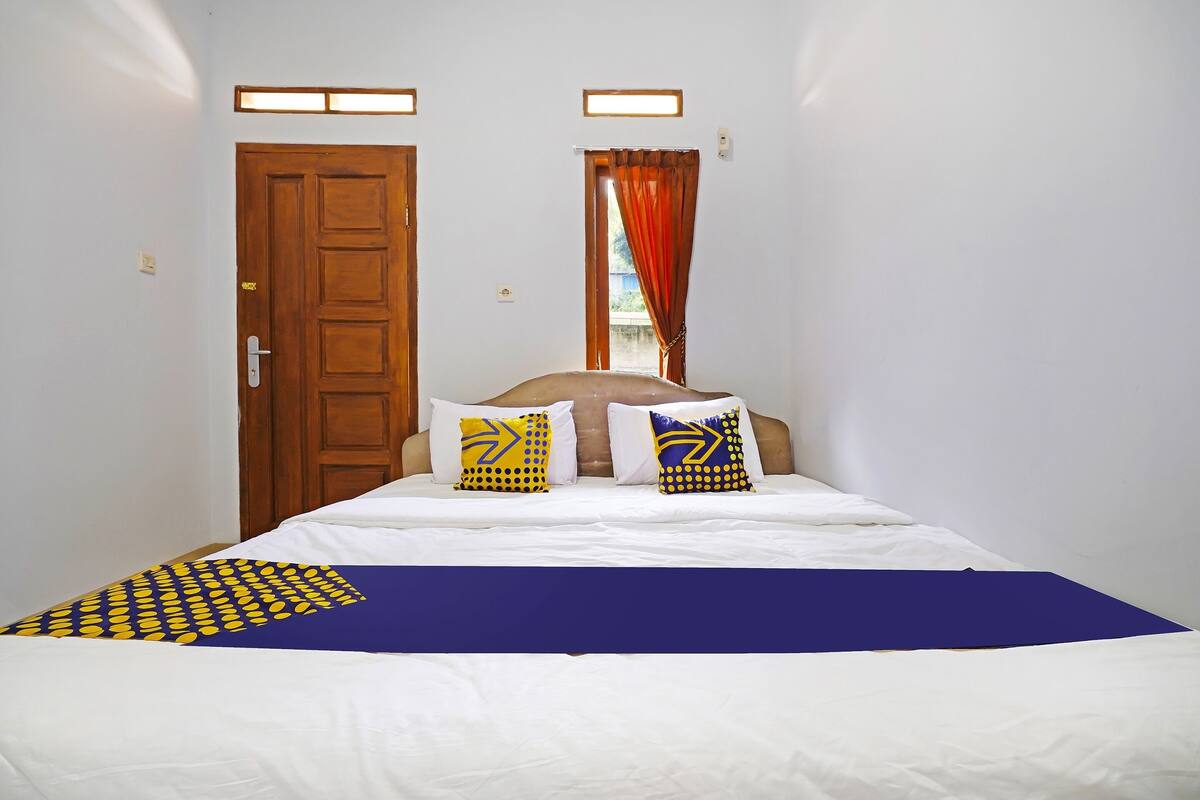 Una habitación de hotel con una cama, una puerta de madera y una ventana con cortinas.