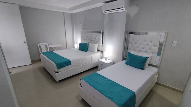 A hotel room with two beds, a white color scheme, and an air conditioning unit.