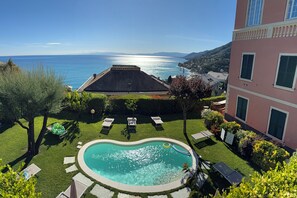A swimming pool with a view of the sea, a building with balconies, and a well-maintained lawn. - Recco "Villa degli Ulivi" with Private Pool and Sea View (Recco)