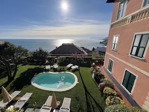 A pool area with lounge chairs and a view of the sea.