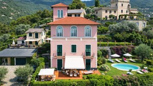 A two-story building with a red-tiled roof, a balcony, and a swimming pool.