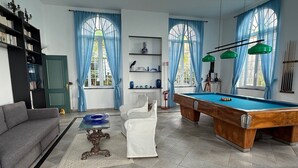 A living room with a pool table, a sofa, a coffee table, and a bookshelf.