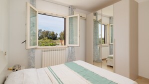 A bedroom with a bed, a window, a radiator, and a mirror. - VIlla Di Vina - SARDINIA UNLIMITED (Alghero)