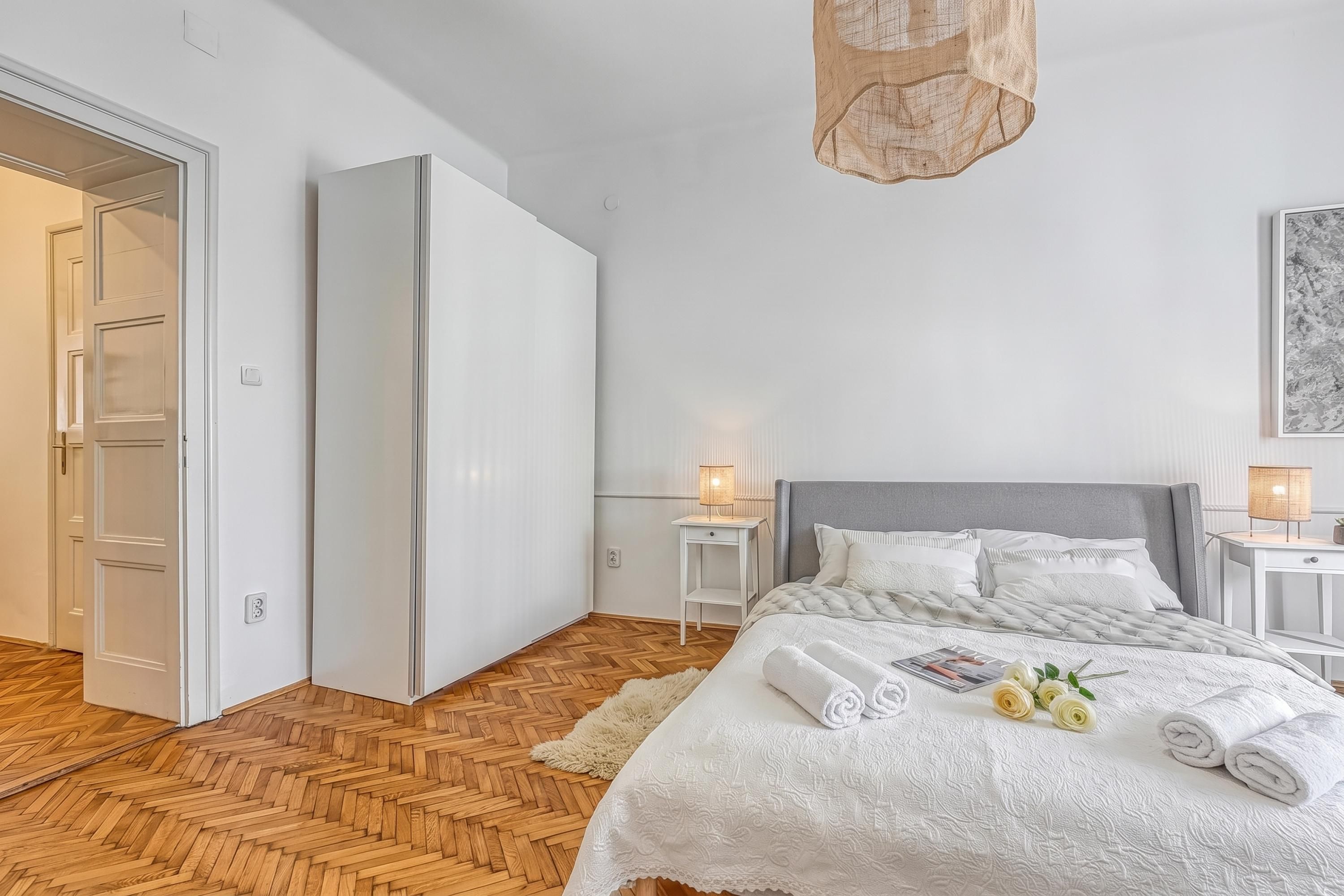 A bedroom with a bed, nightstands, a lamp, and a wardrobe.