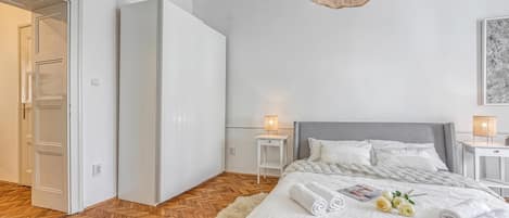 Une chambre à coucher avec un lit, des tables de chevet, une lampe et une armoire.