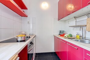 A compact kitchen with red cabinets, a stove, and a sink. - Spacious Apartment In Heart Of Zagreb (Zagreb)