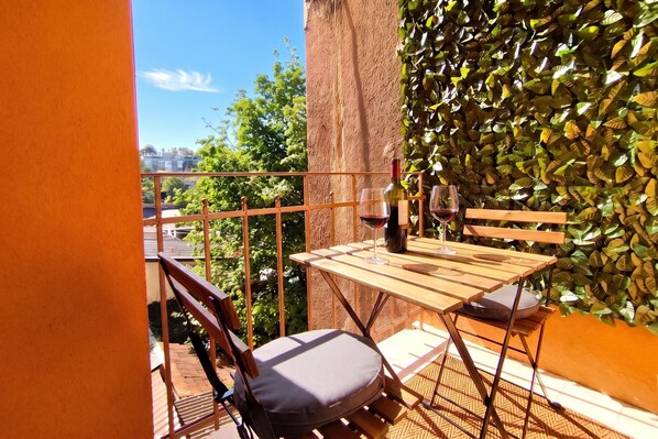 A balcony with a table, chairs, a wine bottle, and glasses.