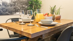 A dining table with two wine glasses, a pitcher of orange juice, a bowl of fruit, and a pineapple. - Woodbury 2-5 (Lancaster)