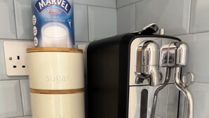 A coffee maker with a milk frother and a container labeled with sugar, coffee, and tea compartments. - Lovely 1-bed Apartment in Town Centre Colchester (Colchester)