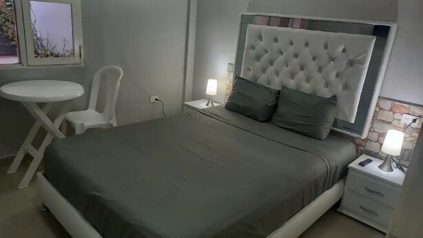 A neatly arranged bedroom with a bed, bedside tables, a chair, and a small table.