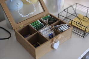 Una caja de madera con compartimentos que contienen diversos objetos, entre ellos paquetes verdes y un objeto blanco con forma de corazón.