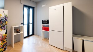 A modern kitchen with a white refrigerator, a microwave, and a wooden herringboard. - Loft33 (Barletta)